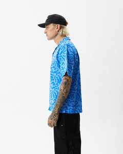 side view of the Afends Men's Icebergs Short Sleeve Shirt in Arctic on a model posing with his hands at his sides