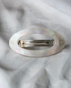the Horace Maria oval Hair Clip in cream shot from above laying on grey fabric