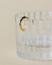 Load image into Gallery viewer, the Horace Hammered Ear Cuff in gold hanging off the side of a fluted glass dish
