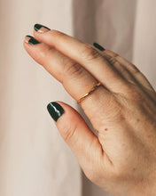 Load image into Gallery viewer, the Horace Wavy Ring in gold shown on the pointer finger of a hand with dark green nail polish
