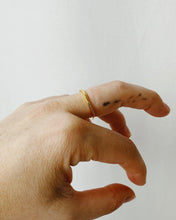 Load image into Gallery viewer, the Horace Wavy Ring in gold worn on the middle finger of a hand
