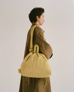 a model wearing the Ölend Ona Soft Bag in lime shot from a side view