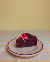 Load image into Gallery viewer, The Wednesday Co Chocolate Cake Candle sitting on a plate on a striped table cloth in front of a yellow background
