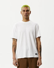 Load image into Gallery viewer, the Afends Men&#39;s Classic Hemp Retro Tee in White on a model posing in front of a white background looking straight into the camera
