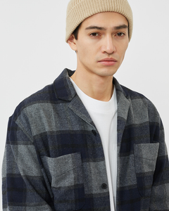 Close up of a model wearing the Minimum Men's Laurel Overshirt in Grey Melange unbuttoned over a white t-shirt pared with a beige beanie