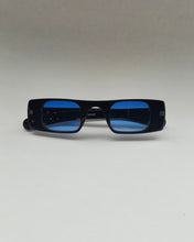 Load image into Gallery viewer, the Spitfire Cut Seven Sunglasses in black with blue lens laying on a neutral background
