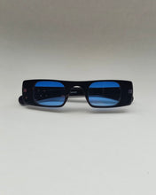 Load image into Gallery viewer, the Spitfire Cut Seven Sunglasses in black with blue lens laying on a neutral background