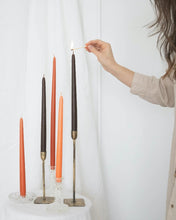 Load image into Gallery viewer, five Socco Designs Taper Candles in varying stands, one is being lit with a match by a hand entering the frame from the right