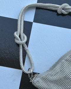 close up of the knot strap of the Slouchy Crystal Shoulder Bag in Silver laying on a checkerboard background