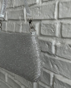 close up of the Crystal Clutch Bag in Silver against a white brick background