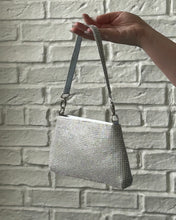 Load image into Gallery viewer, Crystal Clutch Bag in Silver held up by a hand against a white brick background
