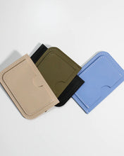 Load image into Gallery viewer, the Small Hours Leather Card Case in Almond laying on top of a pile of different coloured wallets on a white background
