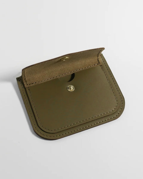 the Small Hours Leather Mini Wallet in Olive laying on a white background on an angle with the front snap pocket open