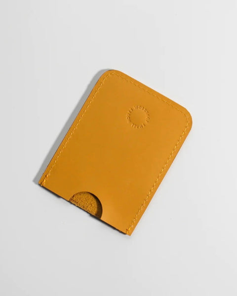 the front side of the Small Hours Slim Leather Card Holder in Yellow laying flat on an angle against a white background 