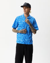 Load image into Gallery viewer, the Afends Men&#39;s Icebergs Short Sleeve Shirt in Arctic on a model posing with one hand on his collar and his head turned to one side
