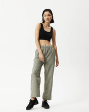 Load image into Gallery viewer, Afends Women&#39;s Octave Spray Pant in Olive on a model posing with one knee bent and her eyes toward her right shoulder
