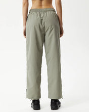 Load image into Gallery viewer, back view of the Afends Women&#39;s Octave Spray Pant in Olive on a model standing with her hands by her sides

