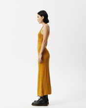 Load image into Gallery viewer, side view of the Afends Women&#39;s Femme Dress in Mustard on a model standing with her hands by her sides
