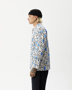 side view of the the Afends Men's Waterfall daisy printed Long Sleeve Shirt in White on a model standing with his hands by his sides