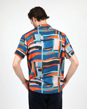 Load image into Gallery viewer, the back view of the Wemoto Men&#39;s Vernon Short Sleeve Shirt in Red on a model posing with his hands in his pockets
