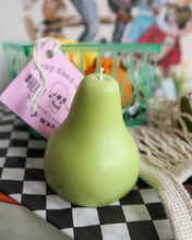 Load image into Gallery viewer, the Drop Dead pear candle sitting on a stack of books beside a net bag
