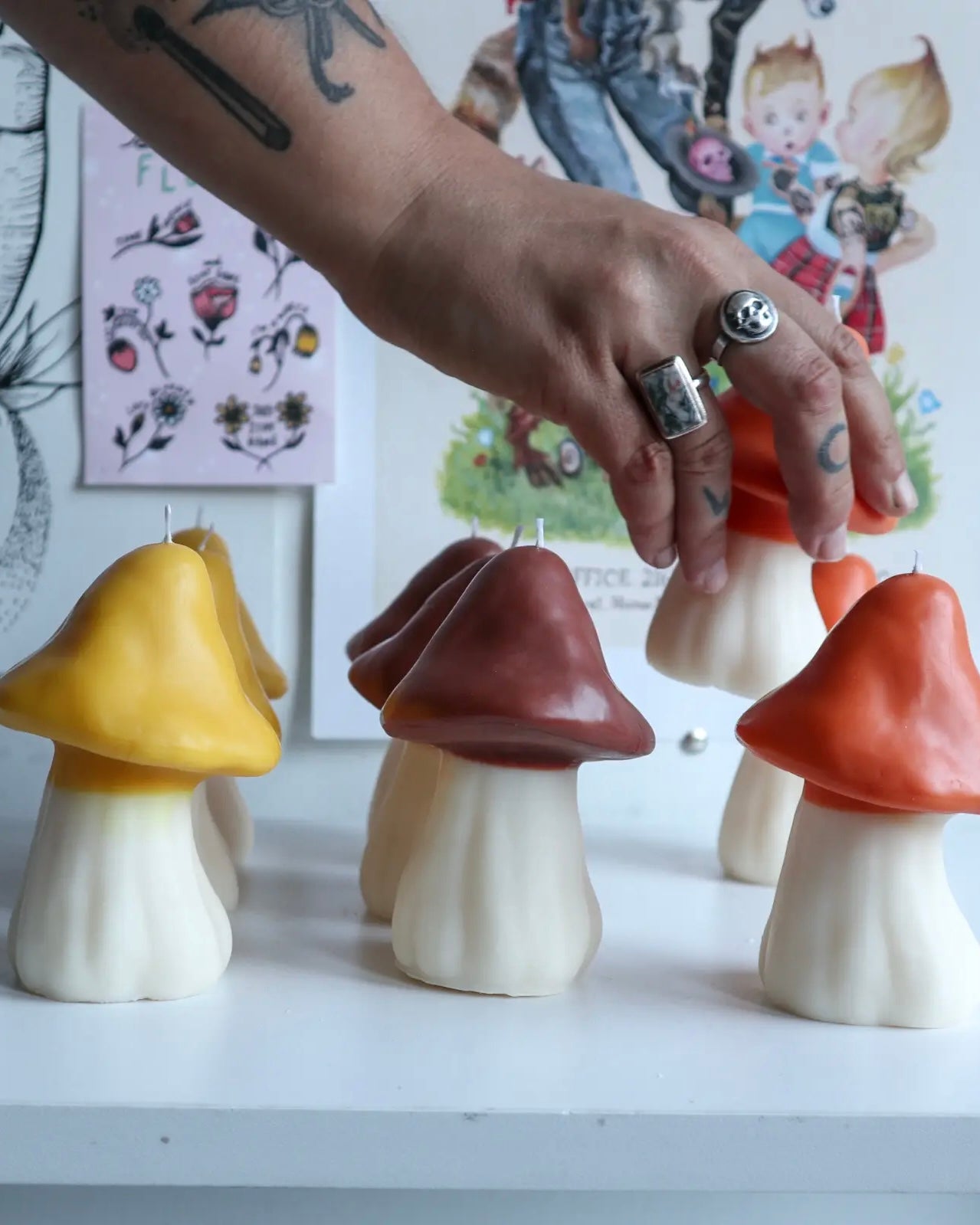 a hand reaching for the Drop Dead Retro Mushroom Candle in a line up of candles