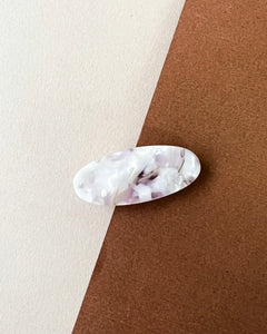 the Horace Lina Hair Clip in pearly lilac shot from overhead in the center of a brown and cream surface