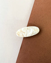 Load image into Gallery viewer, the Horace Lina Hair Clip in cream shot from overhead in the center of a brown and cream surface
