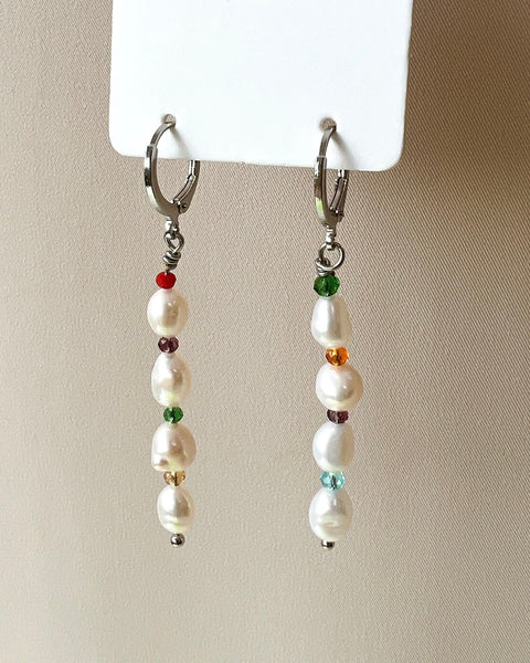 the Horace Bisera pearl and gemstome dangly Earring hanging from a card against a neutral background