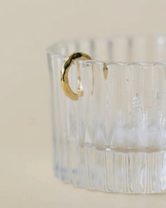 the Horace Hammered Ear Cuff in gold hanging off the side of a fluted glass dish