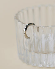 Load image into Gallery viewer, the Horace Hammered Ear Cuff in silver hanging off the side of a fluted glass dish
