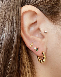the Horace Gemma Stud Earring shown in an ear in the third piercing along with a hoop earring in the first hole and stud in the second