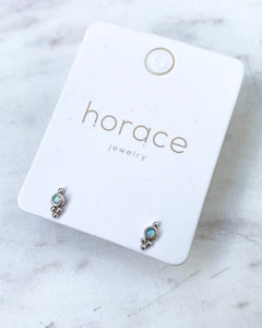the Horace Gemma Stud Earring in silver on a branded card laying on a marble surface