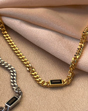 Load image into Gallery viewer, a close up shot of the Horace Nero Necklace in gold and in silver laying flat on folded pieces of fabric
