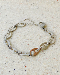 the Horace Roffia stainless steel chain link Bracelet laying flat on a stone background