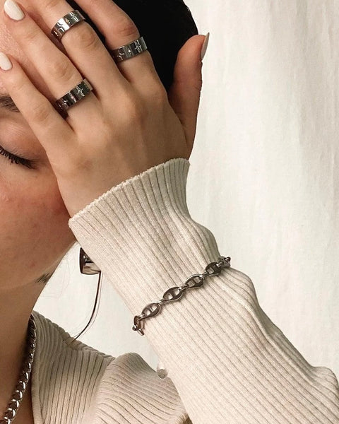 the the Horace Roffia stainless steel chain link Bracelet worn on the outside of a sweater sleeve by a model posing with her head in her hand