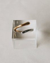 Load image into Gallery viewer, the Horace Dobli Ring in gold and silver sitting in a plexiglass display cube
