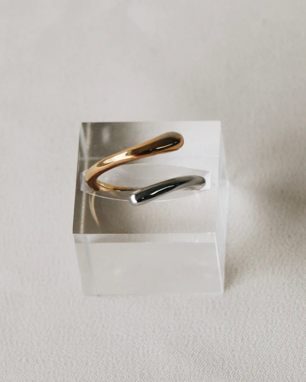 the Horace Dobli Ring in gold and silver sitting in a plexiglass display cube
