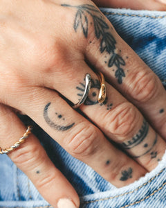the Horace Dobli Ring worn on the middle finger of a model with a tattooed hand resting in her jean pocket