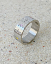 Load image into Gallery viewer, a close up of the Horace Sparka Ring in silver sitting on its side on a speckled stone surface
