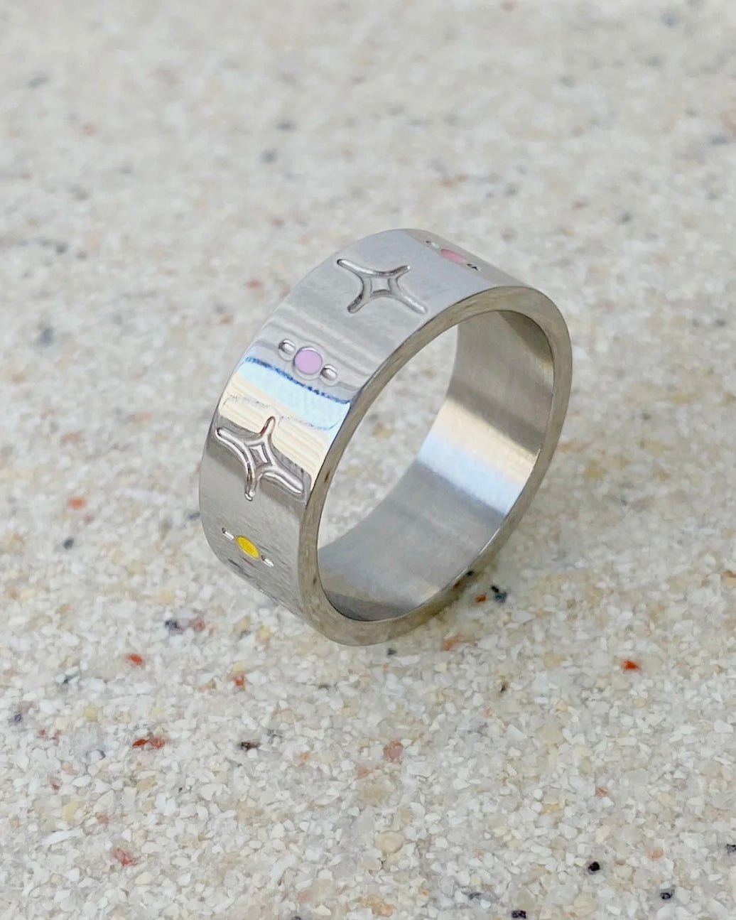 a close up of the Horace Sparka Ring in silver sitting on its side on a speckled stone surface