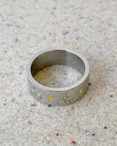 the Horace Sparka Ring in silver laying flat on a speckled stone surface