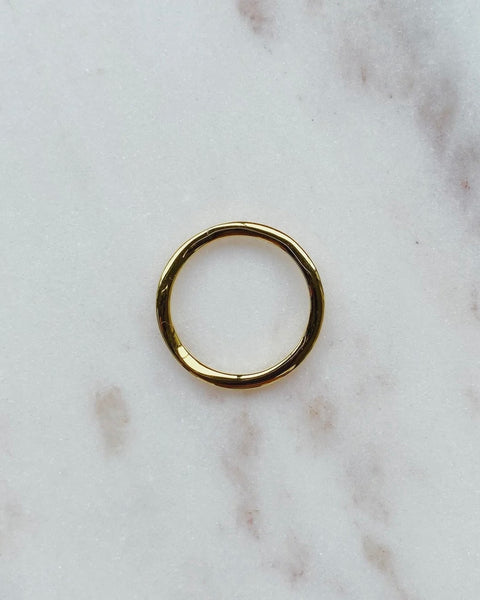 Horace Wavy Ring in gold shot from above laying flat on a marble surface