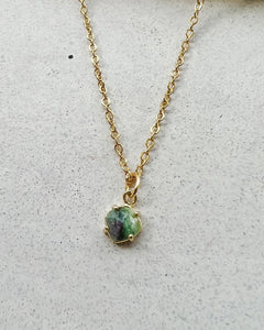 the Horace Zoto Necklace in gold shot with a close up of the green agate gemstone laying flat against a neutral background