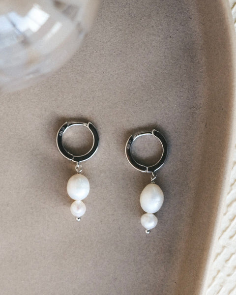 the Horace jewelry silver and pearl Dolkoka Earrings laying flat in a neutral coloured dish shot from above