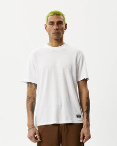 the Afends Men's Classic Hemp Retro Tee in White on a model posing in front of a white background looking straight into the camera