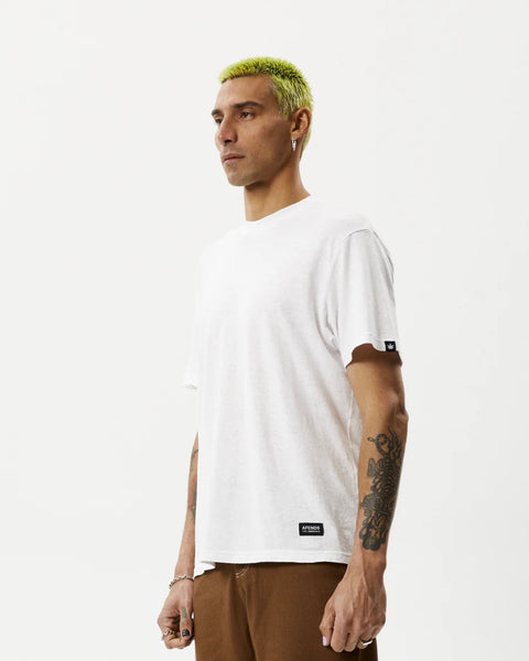 the Afends Men's Classic Hemp Retro Tee in White on a model posing on a side angle in front of a white background