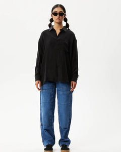 the Afends Women's Gemma Shirt in Black on a model posing in front of a white background