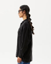 Load image into Gallery viewer, side view of the Afends Women&#39;s Gemma Shirt in Black on a model posing in front of a white background
