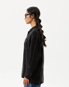 side view of the Afends Women's Gemma Shirt in Black on a model posing in front of a white background